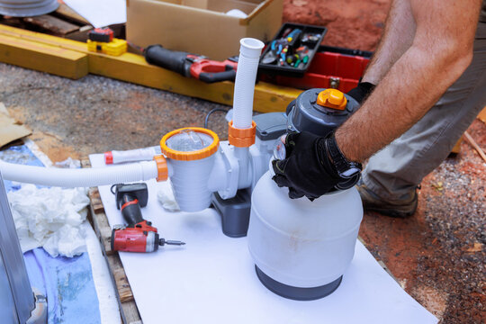 Assembling components of pool filtration system on works day in backyard setting, near swimming pool