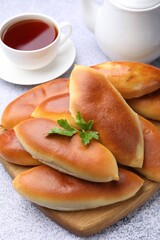 Tasty baked patties and cup of tea on grey textured table