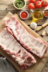 Fototapeta premium Raw pork ribs, spices and tomatoes on wooden table, flat lay