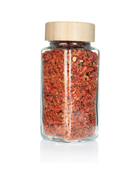 Red chili pepper flakes in spice jar isolated on white