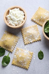 Uncooked ravioli, cottage cheese and spinach on light table, flat lay