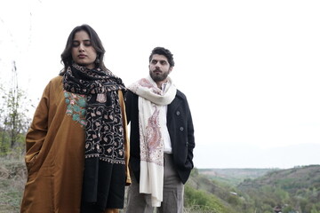 A couple posing in traditional Kashmiri attire, adorned in handwoven shawls and embroidered pherans, showcasing the rich heritage and artistry of Kaar Kash in a styled fashion shoot.

