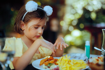  Girl Enjoying her Lunch with Crispy Chicken and french fries. Hungry kid eating with her bare hands in a restaurant
