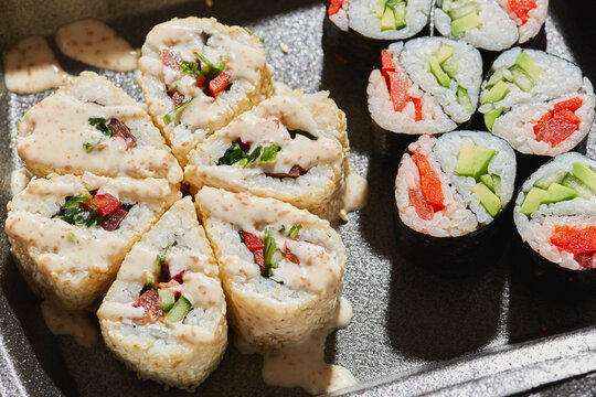 Colorful sushi rolls prepared with fresh ingredients displayed on a dark tray