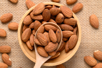 Raw almond nut seed in wooden bowl with spoon, Top view