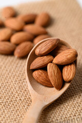 Raw almond nut seed in wooden spoon, Food ingredient