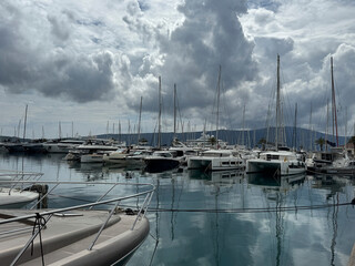 Scenic view of luxury yachts and sailboats docked at Porto Montenegro marina under cloudy skies