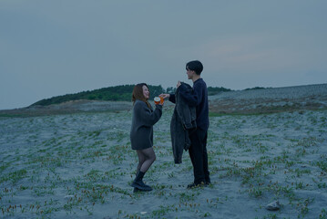 曇りの日の夕方の砂丘を歩く若い男女