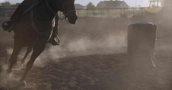 Silhouette of woman riding horse around barrel in beautiful slow motion, medium shot