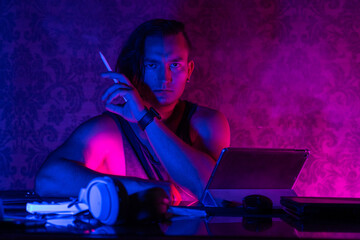 A young caucasian male artist poses confidently with a digital tablet under vibrant neon lighting, reflecting creativity, technology, and modern artistry trends.