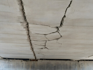 Cracked concrete ceiling with visible damage and structural deterioration, showing hidden cracks and potential safety concerns in building infrastructure