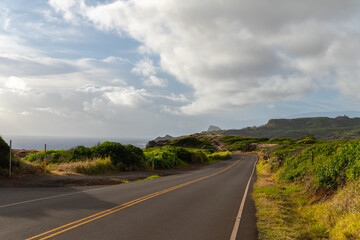 Scenic coastal road winds along the ocean under a cloudy sky, offering a picturesque view.