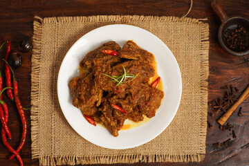 Traditional Indonesian beef rendang served on a white plate with chili garnish. Popular spicy dish from Minangkabau cuisine