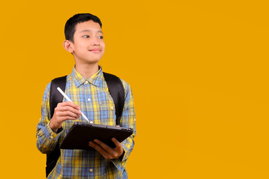 Young Asian Student Boy Holding Digital Tablet And Stylus Looking Thoughtfully To The Side