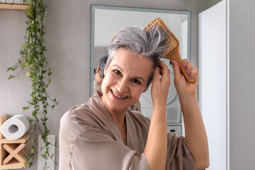 Portrait of a smiling elderly woman of pensioner age with gray hair with a wooden comb in her hands.