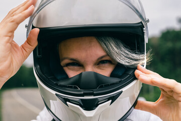 Close-up of mature woman in helmet with gray hair, symbol of confidence, freedom and timeless beauty