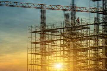 Man working on construction site with scaffold and building with sun set background,scaffolding for construction factory