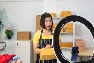 Woman in apron prepares packages for online sales with ring light