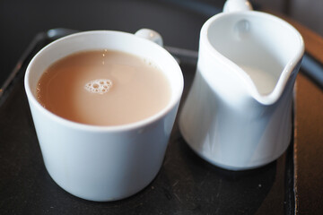 Freshly brewed tea served with cream on a black tray