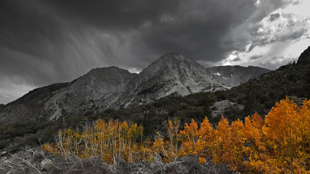 A fall thunderstorm over a mountain peak in Yosemite National Park, California with beautiful peak foliage.