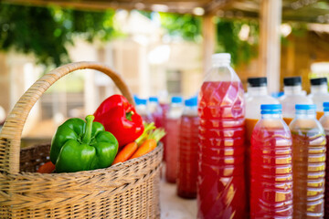 Organic fertilizer bottles with vegetables basket on organic farm with Agricultural students group checking liquid organic fertilizer in background, Fermented compost liquid in plastic bottles DIY