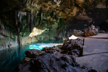 CENOTES Cueva subterránea con agua turquesa iluminada por luz natural y formaciones rocosas...