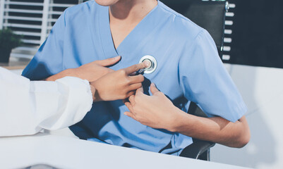 A physician uses a stethoscope to examine a patient's heart during a clinic appointment.
