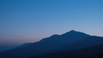Mountain silhouette under twilight sky, serene blue tones blending into dusk, nature's quiet grandeur