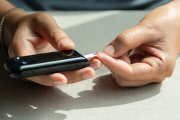 Woman's hands checking diabetes and hyperglycemia with digital blood sugar meter. Healthcare and...