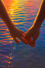 Two Hands Touching Over Colorful Water Reflection