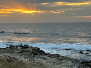 A dramatic sunset at Point La Jolla, California, with sun rays streaking through the clouds,...
