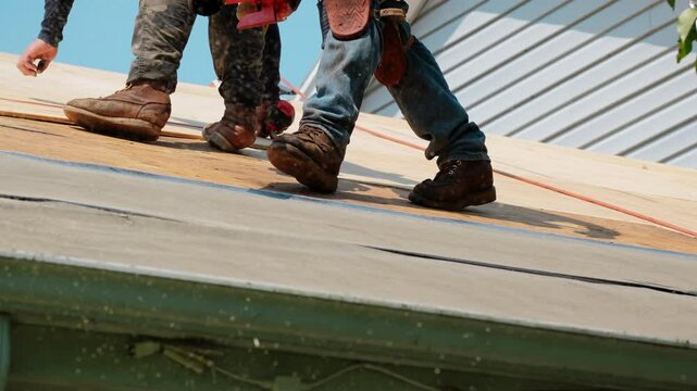 Roofer blowing away dust from the wooden panels on the residential house. Element of roof renovation