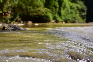 A serene river flows powerfully through a lush, waters cascading down a mountain slope,Red flood water flows from the mountains, Nature of forests and red streams formed by the previous heavy rain