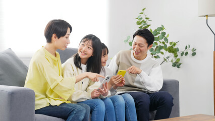笑顔でスマホを見る小学生の女の子の家族