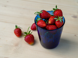 Fresh strawberries on the table in a blue glass cup. The beginning of the berry season. Strawberries from your own garden. Red berries for a healthy snack