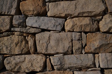 Fototapeta premium A rugged stone wall, textured and earthy tones, basks in sunlight