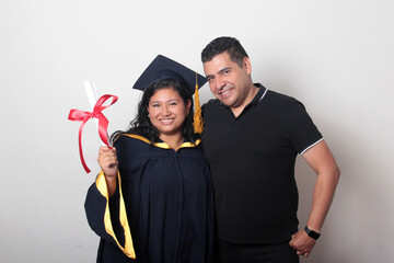 Proud and satisfied single dad with his brunette Latina daughter, a graduate dressed in a cap and...