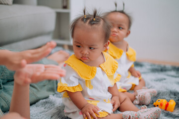 Selective focus shot, Young mother lies on a carpet taking care of her twins while they play with toys in the living room at home.