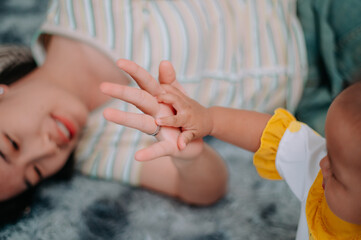 Selective focus shot, Young mother lies on a carpet taking care of her twins while they play with toys in the living room at home.