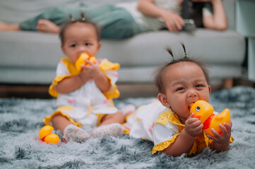 Portrait of Toddler twin girls play with toys on a soft carpet in living room at home.