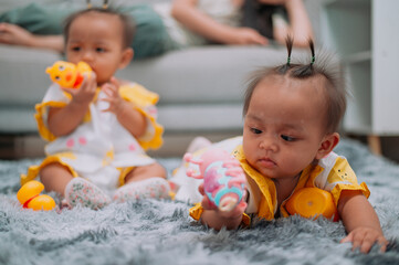 Portrait of Toddler twin girls play with toys on a soft carpet in living room at home.