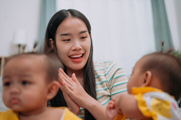 Selective focus shot, Young Asian mother shares a happy moment with her twin daughters while sitting on a soft carpet in a cozy room at home. Leisure activities with family