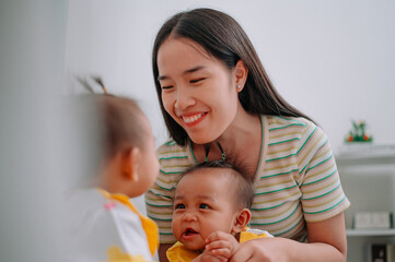 Selective focus shot, Single mother spends happy time with her twin daughters in a warm room at home. Take care of baby with love and care.