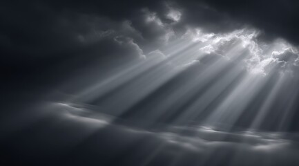 Dramatic grayscale image of sunbeams piercing dark clouds above a low-lying landscape