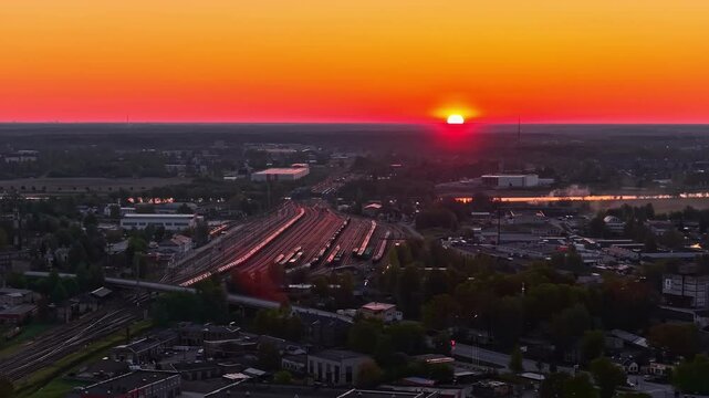 City sunset over railway tracks, aerial view with vibrant orange and red sky
