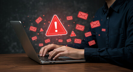 Person typing on laptop surrounded by red email icons and warning signs indicating potential phishing threat