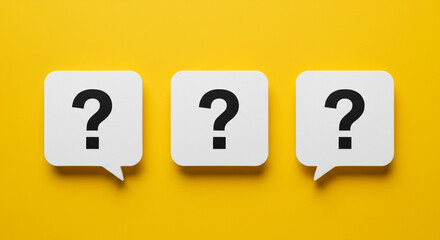 Three white speech bubbles with black question marks on a bright yellow background in a studio shot