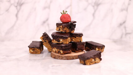 Choco Chip Cookie Brownies are decadent brownie-cookie hybrids featuring a chewy brownie layer stacked over a crunchy chocolate chip cookie base, all coated in a smooth chocolate ganache. Each bar off