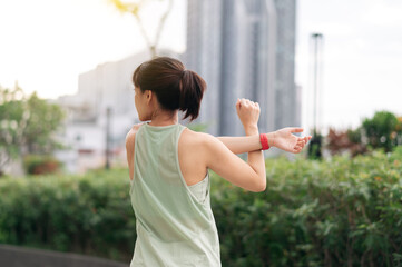 Asian woman fitness workout and yoga stretching exercise reduces shoulder pain inflammation muscle strain and injury risk. Medical wellness in an urban city part of healthcare at sunset
