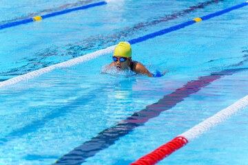 Swimmer child swims breaststroke swimming style in a race swimming pool. Water sports and competition, learning to swim classes for children.